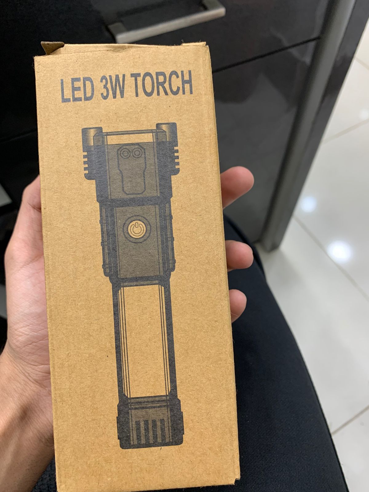 Cardboard box packaging for a LED 3W torch held by a person.