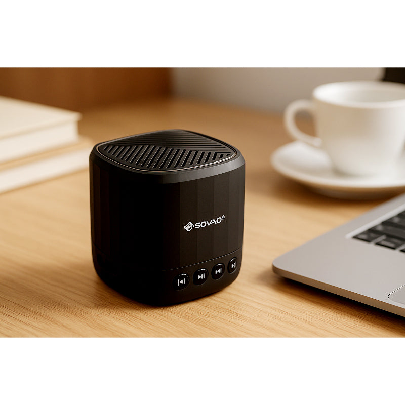 Black Sovao speaker on a wooden desk with a laptop and coffee cup in the background