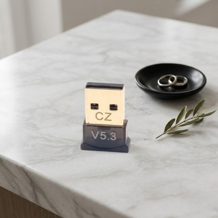 USB adapter with 'CZ' branding on a marble surface with rings and a leaf.