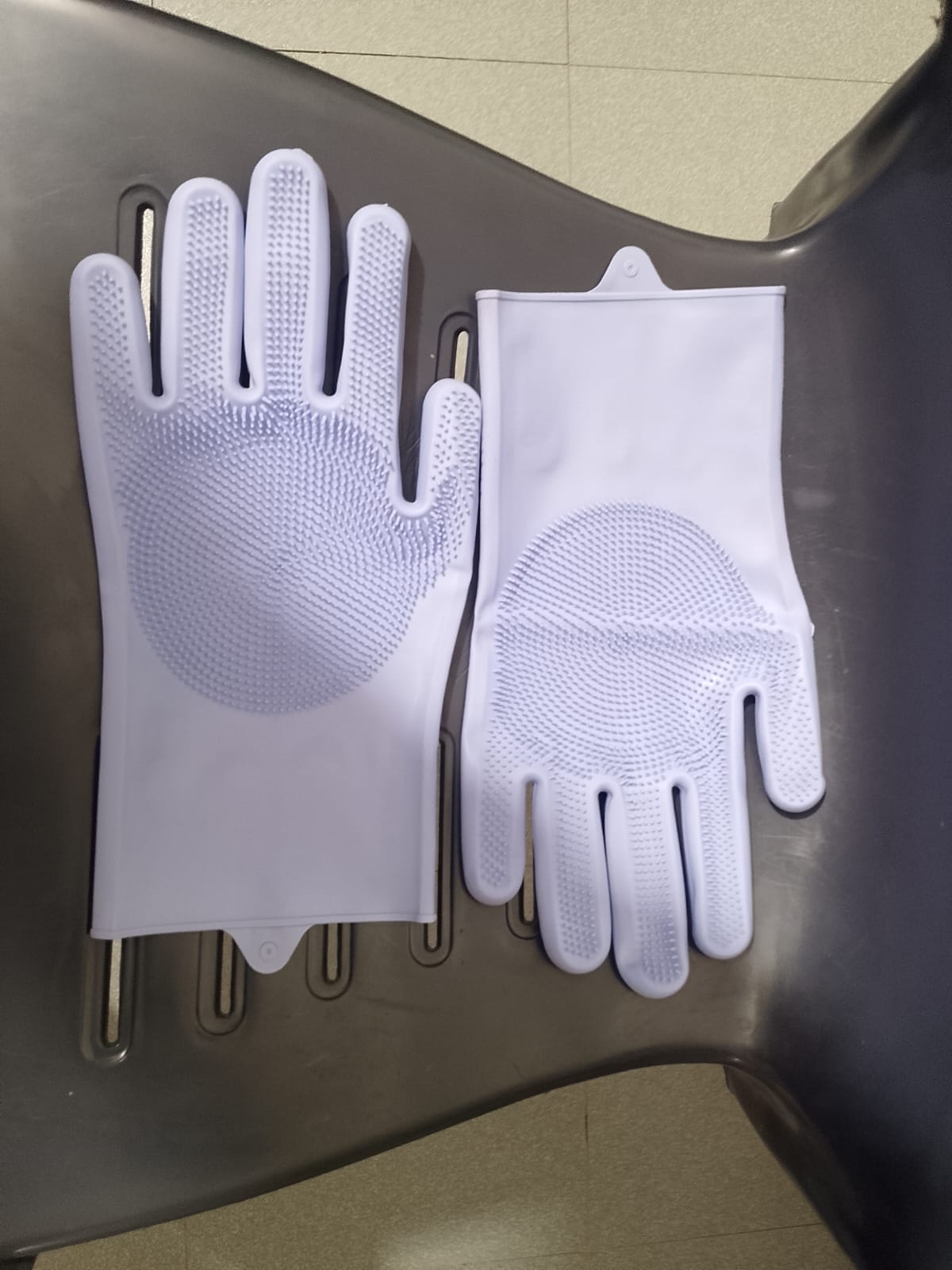 Pair of white gloves with textured palm on a dark surface