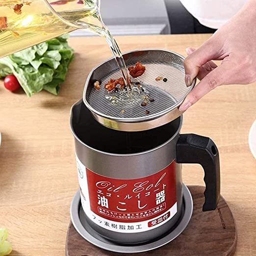Person pouring oil into a kitchen tool on a wooden surface with vegetables in the background