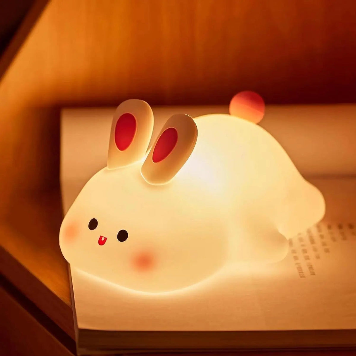 Cute rabbit-shaped night light on a book with a warm glow