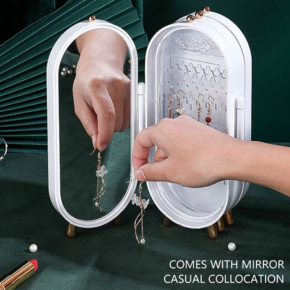 Person organizing earrings in a jewelry organizer with mirror on a green background
