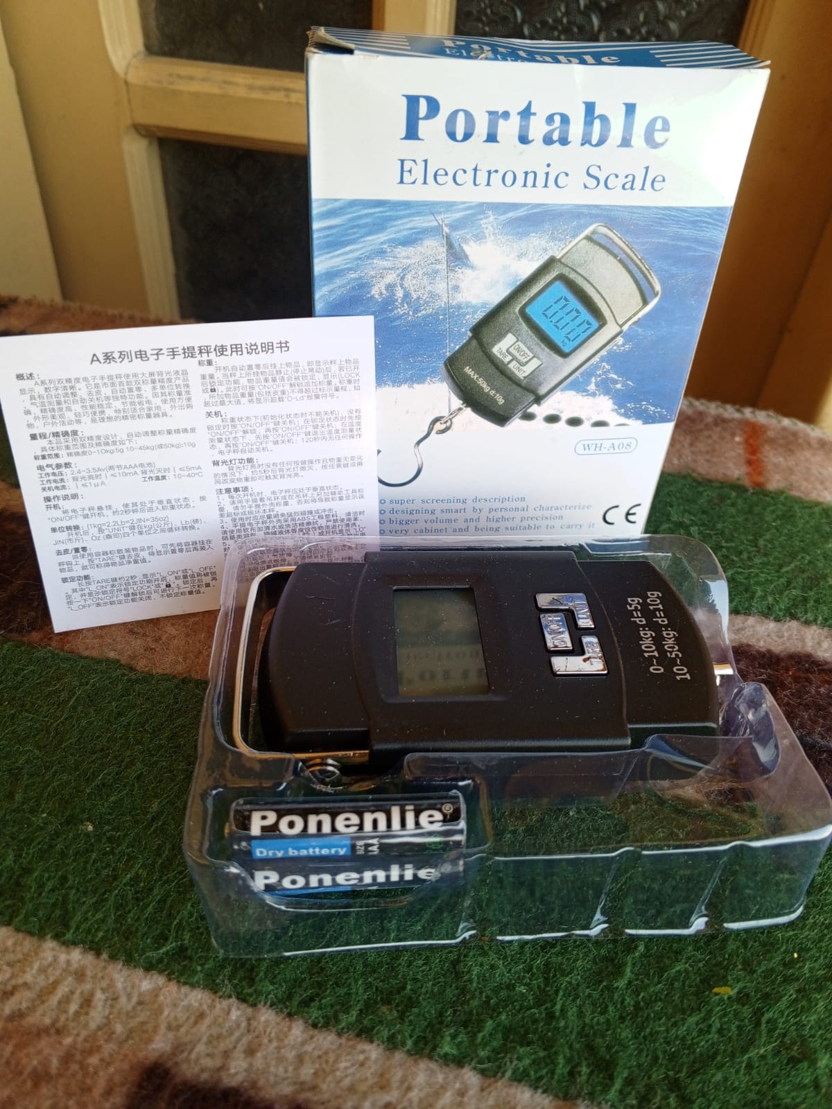 Portable electronic scale with Ponentie branding and packaging on a carpeted floor.