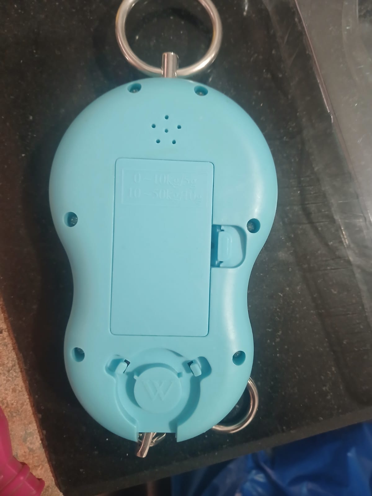 Turquoise keychain device with a keyring on a dark surface
