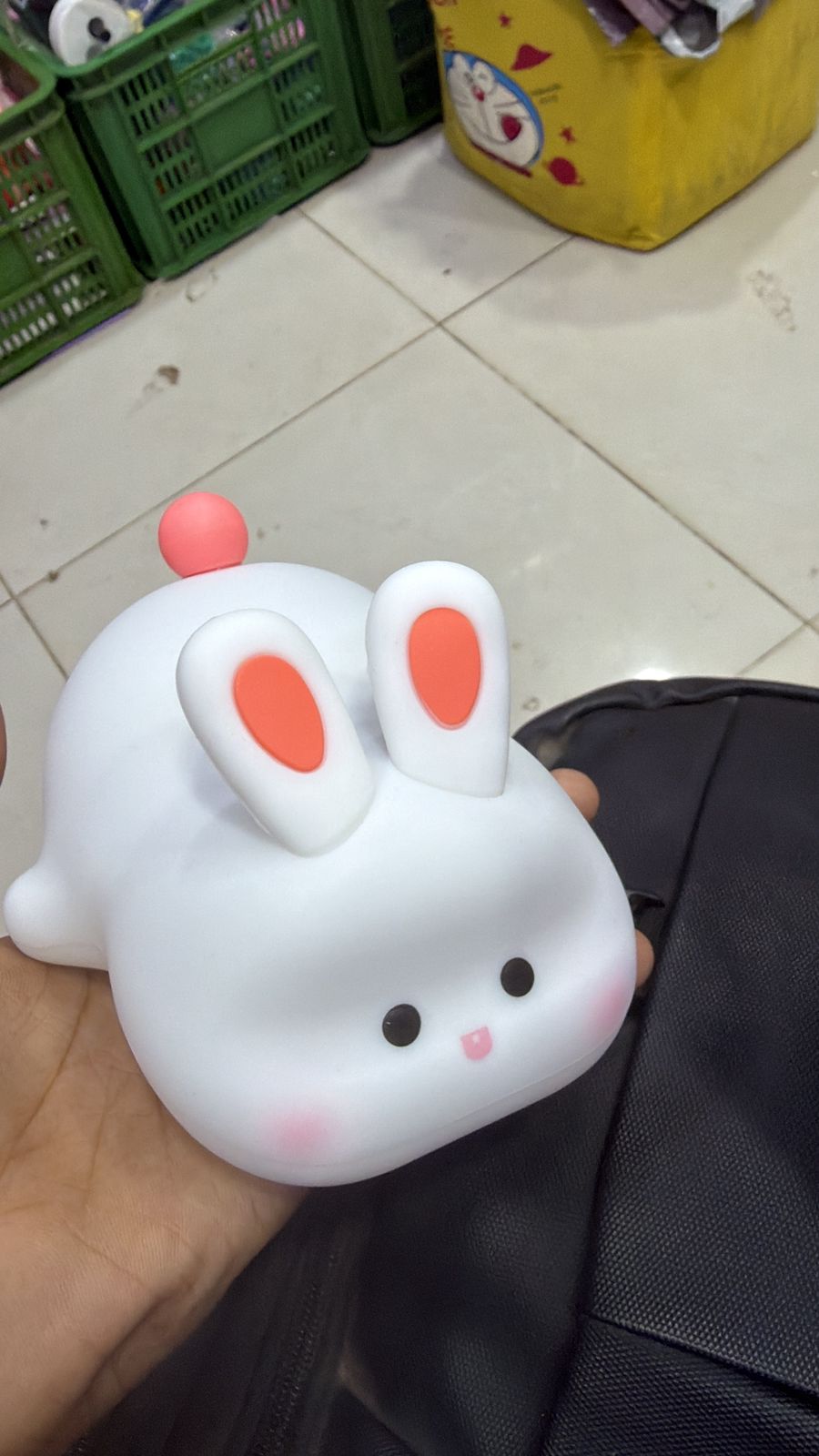 Cute rabbit-shaped object held in a hand with a tiled floor background