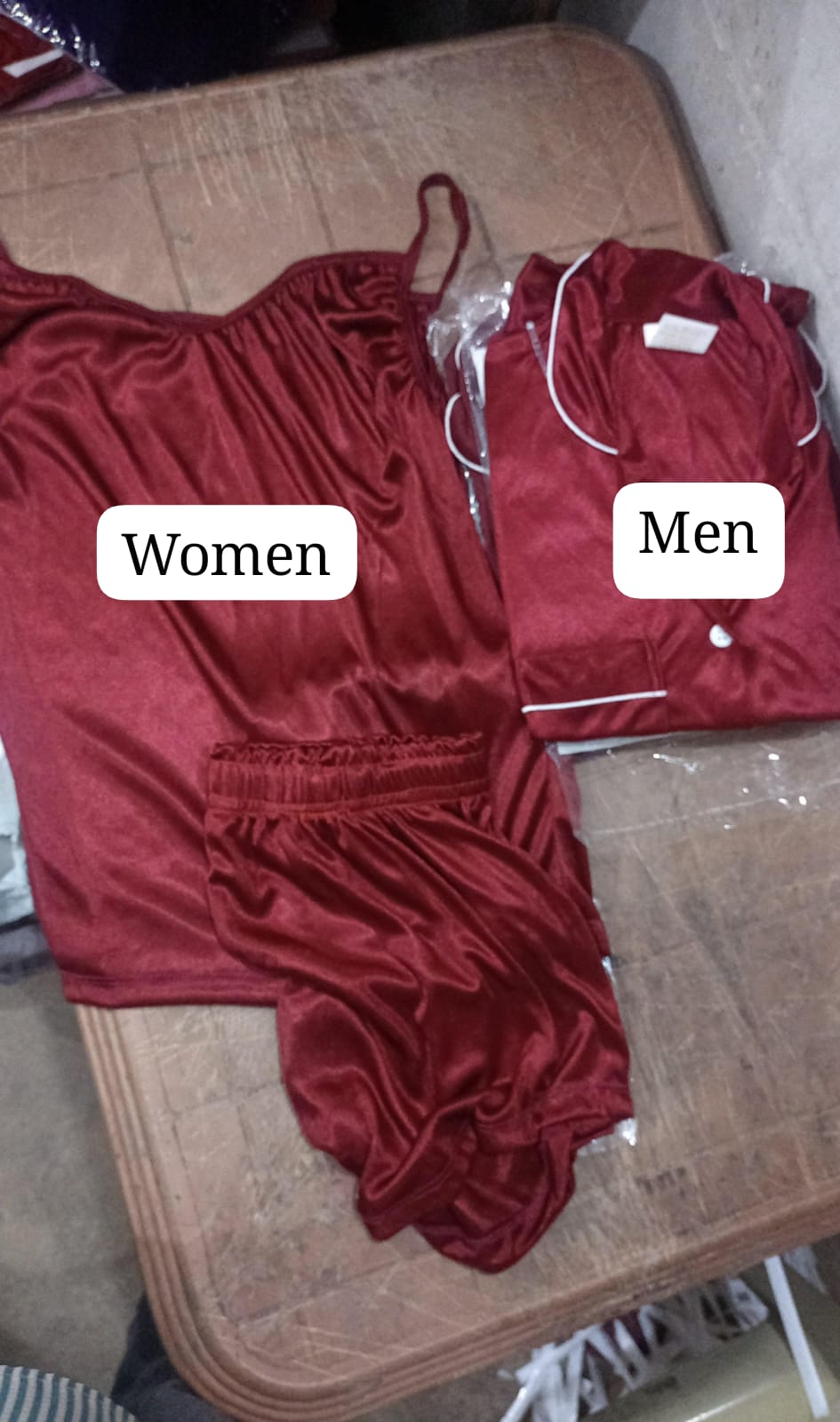Red satin garment labeled 'Women' on the left and 'Men' on the right, on a cardboard surface.