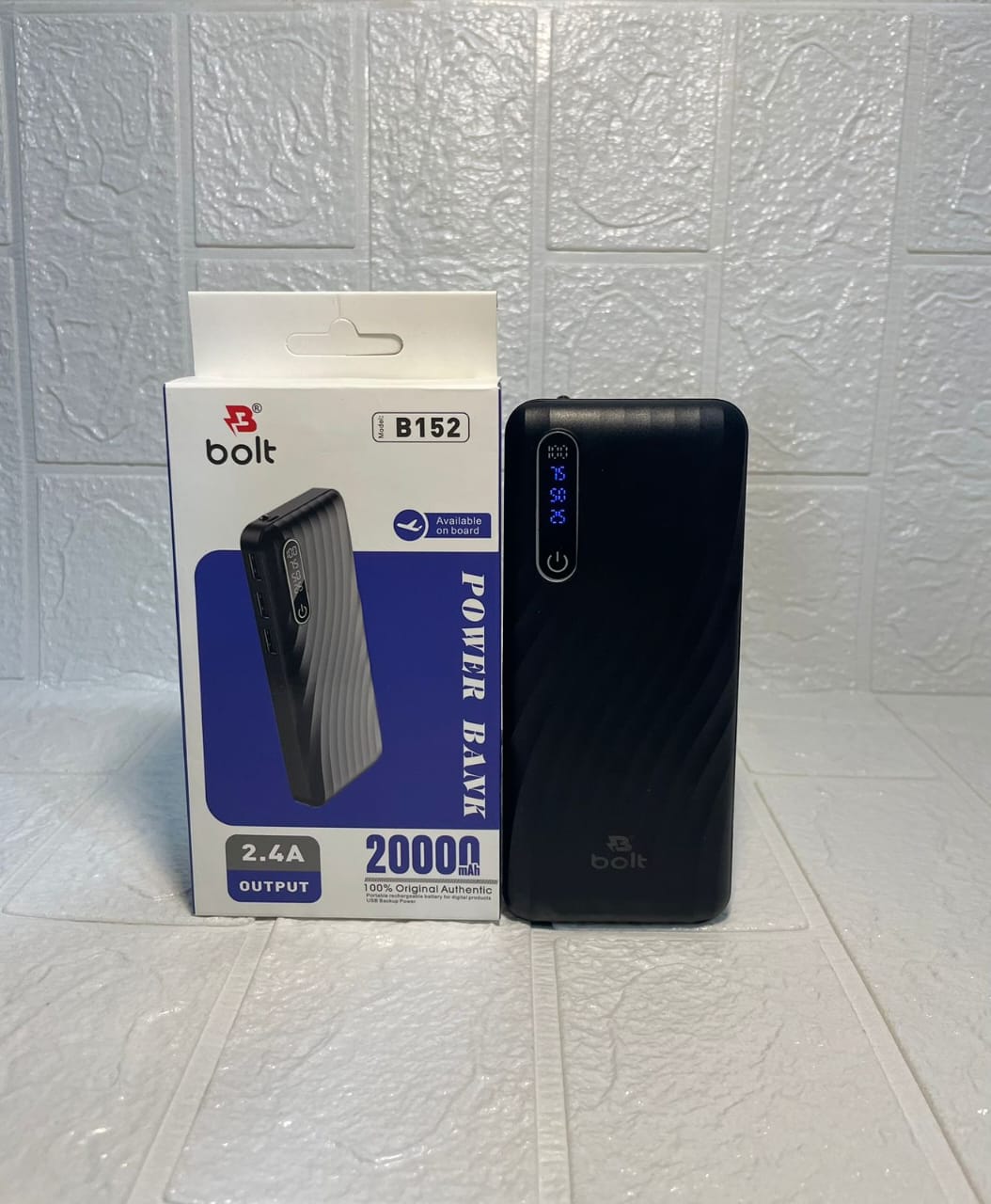 A black Bolt B152 power bank standing next to its white and blue retail packaging box on a light-colored textured tile floor.