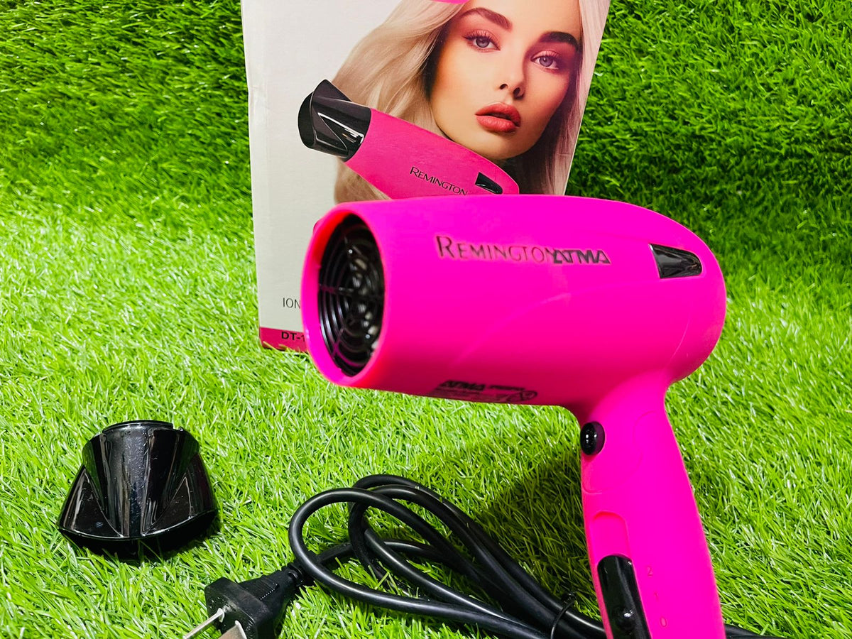 Pink Remington hair dryer on grass with a product packaging featuring a model.