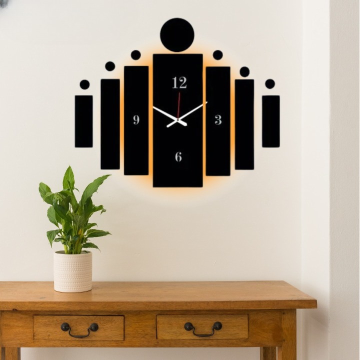 Modern wall clock with black and white design on a white wall above a wooden table with a plant.