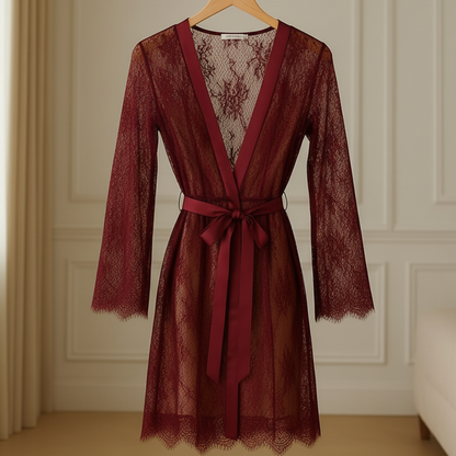 Red lace dress with a belt on a hanger against a neutral wall.
