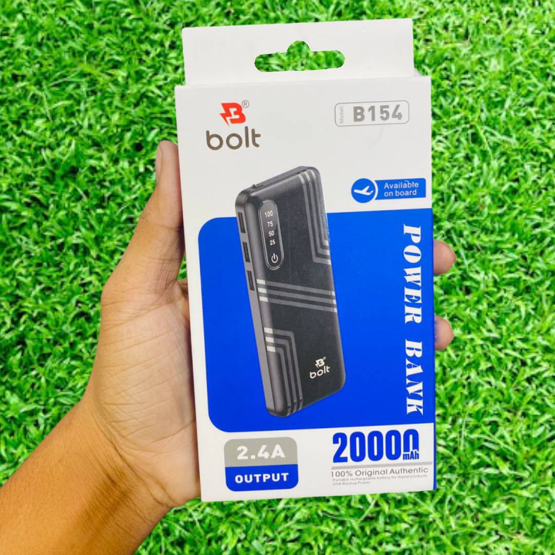 A hand holds a boxed Bolt brand power bank against a bright green grass-like background. The retail packaging is white and blue, showing a black power bank with a gray geometric pattern and text including 'POWER BANK', '20000mAh', '2.