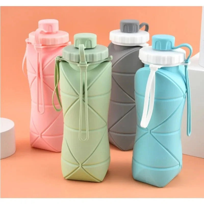 Set of four collapsible water bottles in pink, green, gray, and blue on a peach background.